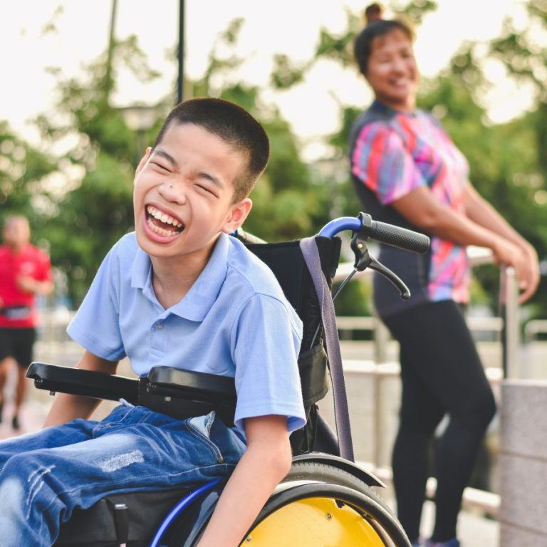 Young individual laughing, with his disability support worker also in picture